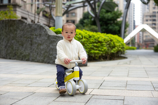 Toddler riding toy bike in park