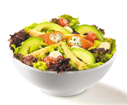 Gourmet salad with cream cheese smoked salmon rolls, avocado, baby corn, hearts of palm and cherry tomatoes in a white bowl isolated on white background