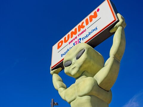 Dunkin&rsquo; restaurant sign held up by green extraterrestrial alien. Roswell is famous for alien mythology  &mdash; Roswell, New Mexico, November 12, 2025