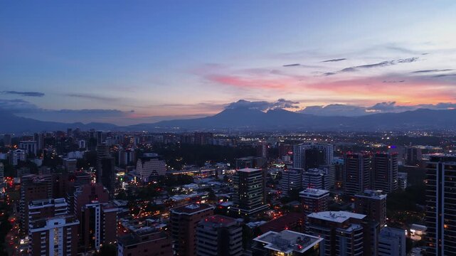 Vista de altura de Ciudad de Guatemala con rascacielos residenciales y luces urbanas de noche. Atardecer dram&aacute;tico y colorido sobre el horizonte de la Ciudad de Guatemala.