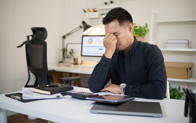 Fototapeta premium Stressed entrepreneur sitting alone at desk, concept of burnout, business problems, mental fatigue, and workplace pressure.