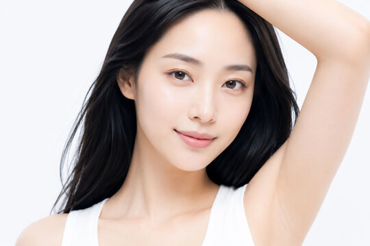 白い無地背景で腕を上げながら自然に微笑むロングヘアの若い女性の透明感ある素肌と清潔感を表現したボディケア美容ポートレート