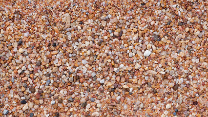 Fototapeta premium Coarse sand and small colorful pebbles texture background, top view of gravel surface.