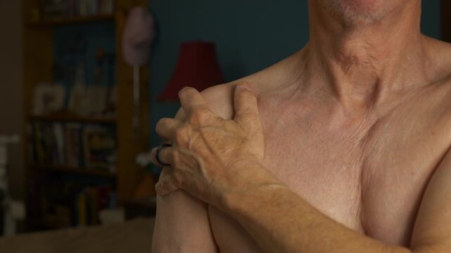 A mature man rubbing his sore shoulder