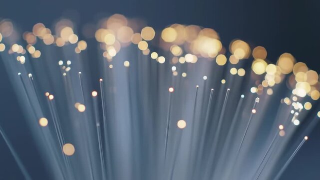 Close-up of glowing fiber optic strands, emitting warm light and creating a bokeh effect, symbolizing data transfer and digital connections, technology concept