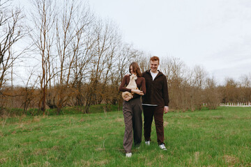 Obraz premium Outdoor family scene with a goat kid, a relaxed walk in a sunlit field, casual clothing, gentle breeze, natural colors, a candid moment of togetherness amid open nature