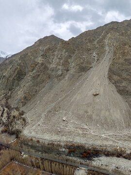 Aerial view of a significant rockfall and landslide on a steep mountain slope with rocky debris and sparse vegetation near Ghawari, Gilgit Baltistan, Pakistan.