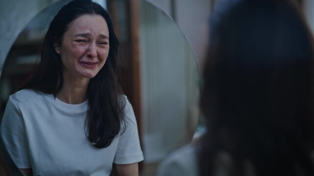 Unhappy lady crying deeply experiencing emotional distress in dark room closeup.