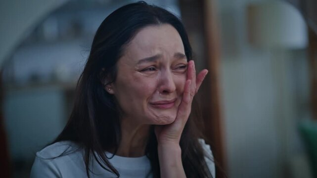 Young woman crying bitterly looking reflection mirror home closeup. Unhappy lady
