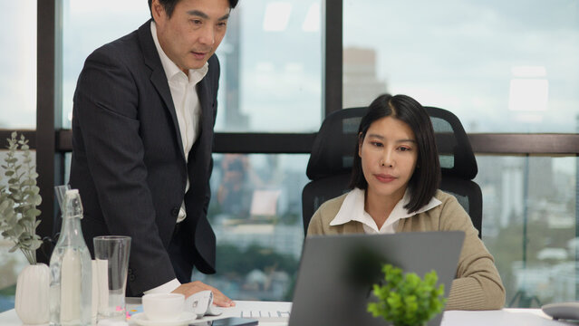 Male Manager Standing Over Female Employee During Tense Office Meeting