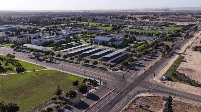 Drone push in showing the modern campus of Clovis Community College in Fresno, California, highlighting its architecture, green spaces, and parking lots with solar panel carports