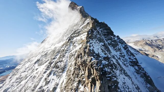 Dramatic FPV drone flight following the snowy summit ridge of the Matterhorn in Switzerland. Cinematic aerial views reveal the iconic alpine peak, glaciers, and rugged mountain terrain.