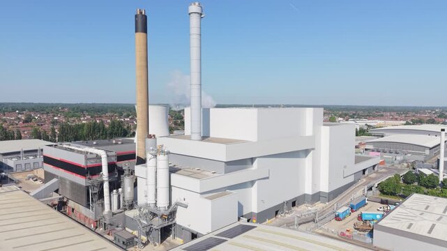 This aerial perspective shows a modern multi fuel power station in operation. Smoke rises from one tall stack on a clear, sunny day.