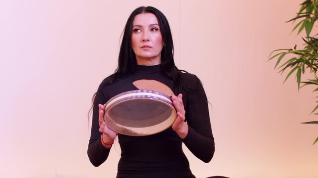 Meditation process. Zen atmosphere. Female turning frame drum during concentration session in studio. Peaceful health balance therapy.
