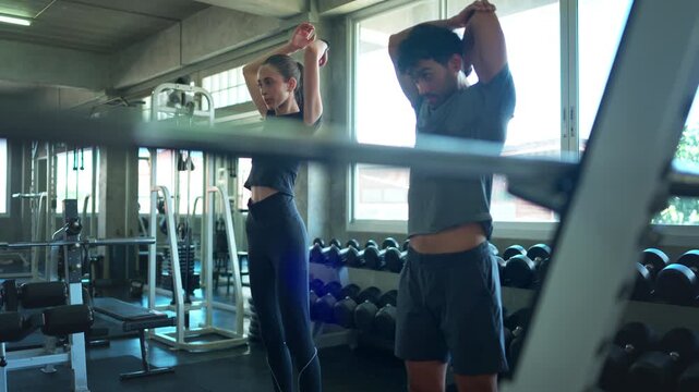 Personal trainer and beginner warm up before performing step aerobics exercises together in a fitness gym