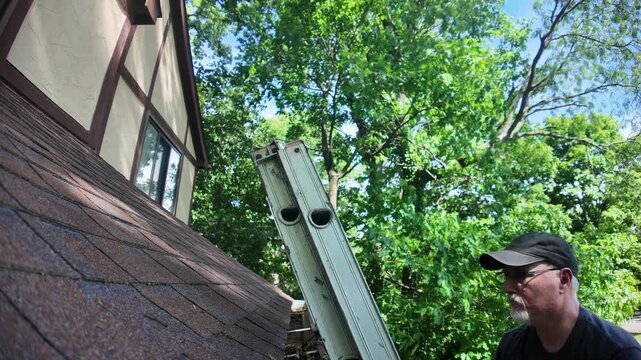 Man climbing ladder to clear gutter on his house