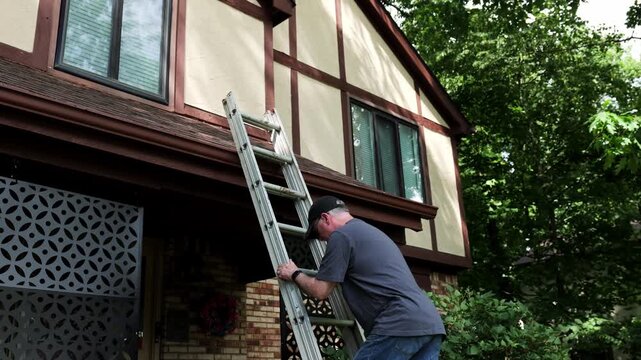 Man climbing ladder to clean his gutter