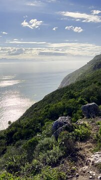 Mom and twin sisters hiking on trail at scenic Robberg nature reserve. Vertical