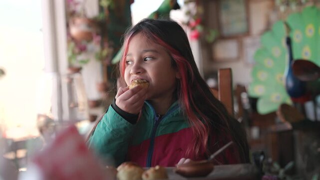 Little girl eating bread at a table, capturing a simple childhood and family meal moment.