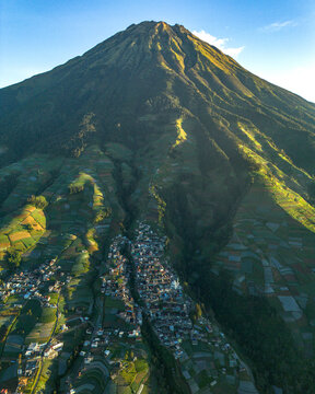 Aerial view of Nepal Van Java village nestled at the base of Mount Sumbing with terraced agricultural fields and lush green slopes in Kecamatan Kaliangkrik, Jawa Tengah, Indonesia.