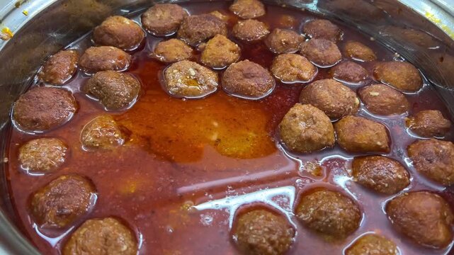Delicious malai kofta served at a vegetarian wedding; professional food photography of traditional North Indian royal paneer dumplings curry, Indian marriage banquet food.