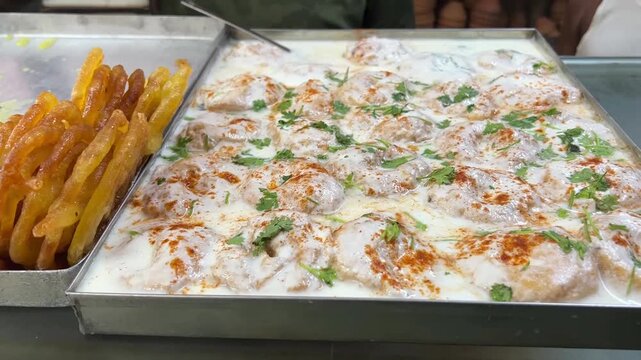 A delightful festive platter of hot, crispy golden jalebis served alongside cool, tangy dahi badas garnished with spices and chutneys, India.