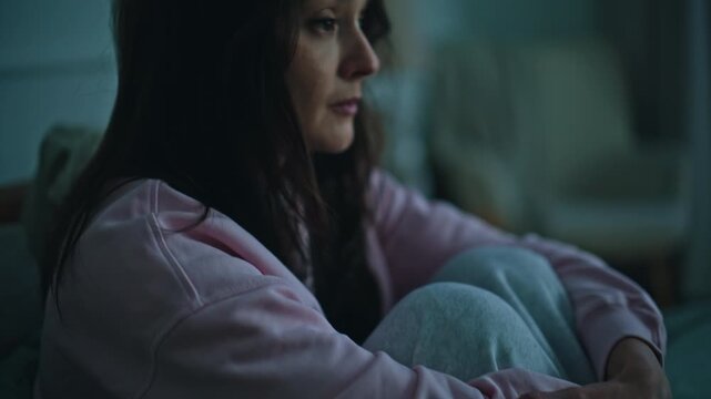 Unhappy lady sitting bed with pensive look at evening closeup. Emotionless woman