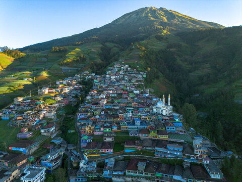 Aerial view of the colorful houses of Nepal Van Java village on the lush slopes of Mount Sumbing with terraced fields and a mosque in Kecamatan Kaliangkrik, Jawa Tengah, Indonesia.