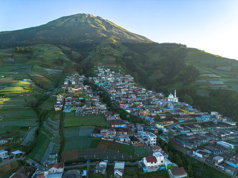 Aerial view of Nepal Van Java village nestled on the slopes of Mount Sumbing with colorful houses and terraced vegetable fields in Kecamatan Kaliangkrik, Jawa Tengah, Indonesia.