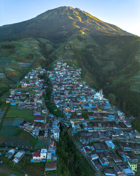Aerial view of Nepal Van Java village nestled on the slopes of Mount Sumbing with colorful houses, terraced vegetable fields, and a mosque in Kecamatan Kaliangkrik, Jawa Tengah, Indonesia.