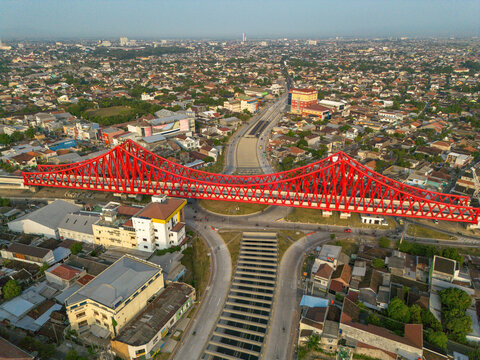 Aerial view of Jembatan Kereta Api Joglo, a prominent red steel railway bridge spanning over an urban intersection in Kecamatan Banjarsari, Jawa Tengah, Indonesia.