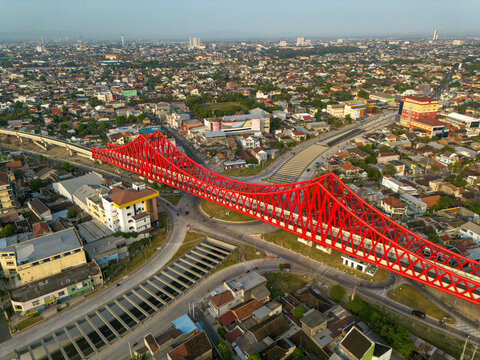 Aerial view of the bright red Jembatan Kereta Api Joglo railway bridge spanning over the intersection in Surakarta, Jawa Tengah, Indonesia.