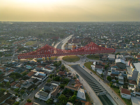 Aerial view of the red Jembatan Kereta Api Joglo railway bridge spanning over a roundabout and urban roads in Kecamatan Banjarsari, Jawa Tengah, Indonesia.