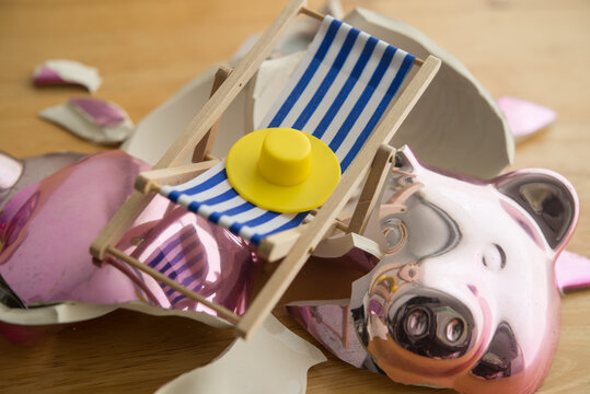 Closeup beach chair and sun hat inside the broken piggy bank. Spending savings account for travel holiday, personal loan, out of money, financial problem, poor financial management, bankruptcy concept