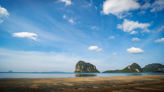 Beautiful sunny day at a tropical beach, white clouds drifting over the turquoise sea.