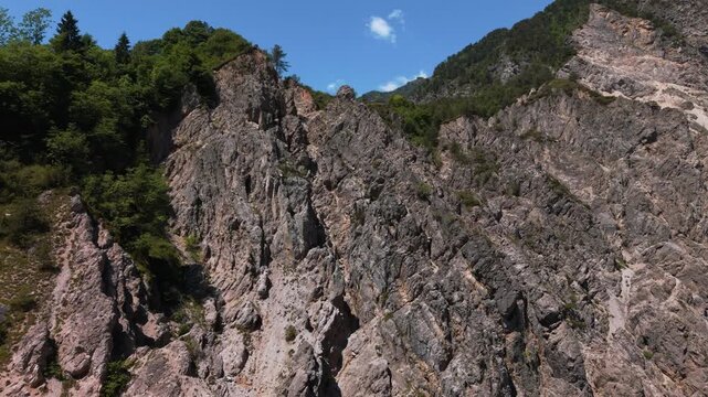 Steep rocky cliffs in Parco Naturale Dolomiti Friulane. Scenic mountain panorama with vegetation. Aerial