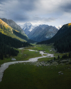 Aerial view of Boris Yeltsin Peak towering over the lush green Jety-Oguz valley with a winding river and dense coniferous forests in Jety-Oguz, Issyk-Kul Region, Kyrgyzstan.