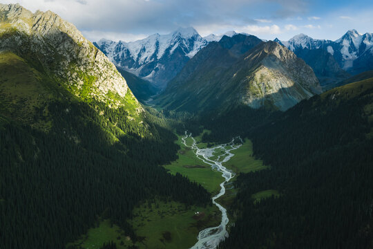 Aerial view of Boris Yeltsin Peak towering over the lush Jety-Oguz valley with a winding river and dense coniferous forests in Jety-Oguz, Issyk-Kul Region, Kyrgyzstan.