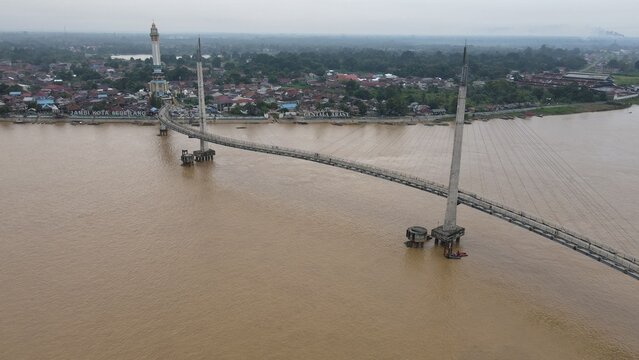 Aerial view of Jembatan Gentala Arasy spanning the Batang Hari river with the city skyline in the background in Kecamatan Jambi Timur, Jambi, Indonesia.
