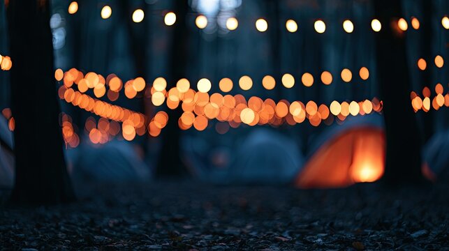 Twinkling string lights illuminate a blurry forest campsite at dusk