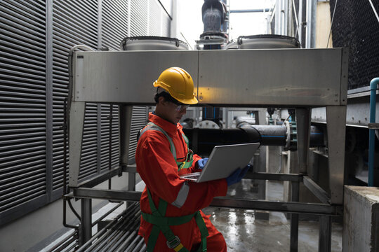 Male engineer using laptop computer inspecting HDPE pipe and fittings for cooling towers, Valve system. Pipe system section of building cooling system. Pipeline of HVAC system of building