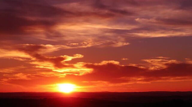 Dramatic orange sunset glows over a dark horizon line