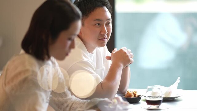 Two people sit at a table, eating together. Woman looks down. Man gazes forward, smiling. They appear relaxed, sharing a quiet meal. Ideal for lifestyle, dining, or relationship scenes