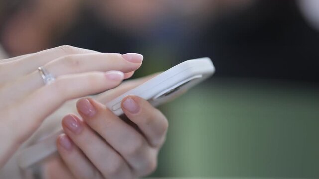 Close-up of hands typing on a smartphone. Fingers move swiftly, suggesting focused attention. Background is softly blurred, highlighting the device interaction