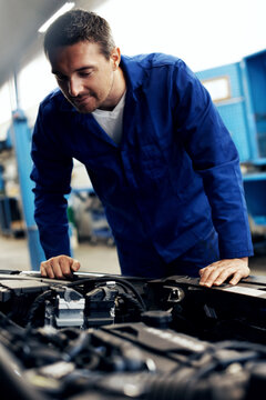 Auto repair, man and engine inspection in workshop for sensor diagnostics, fluid level or safety. Mechanic, person and car service in garage for vehicle maintenance, operational check and calibration