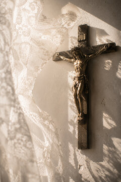 Crucifix framed by a floating lace curtain near a window