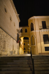 Obraz premium Stone steps lead upward beneath warm night lights. Ancient walls glow softly under gentle illumination. Arched passageways frame historic architecture in quietude