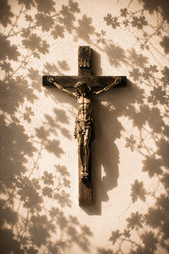 Crucifix under floral shadows on a sunlit plaster wall