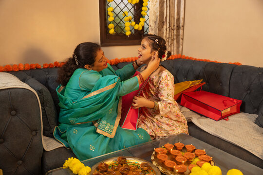 Mother helping daughter with earrings during a festive celebration