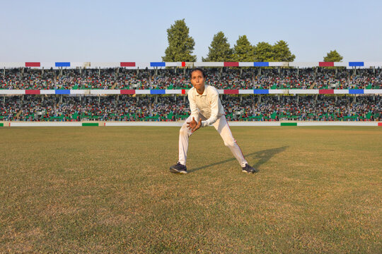 Female cricketer ready to field on a sunny day
